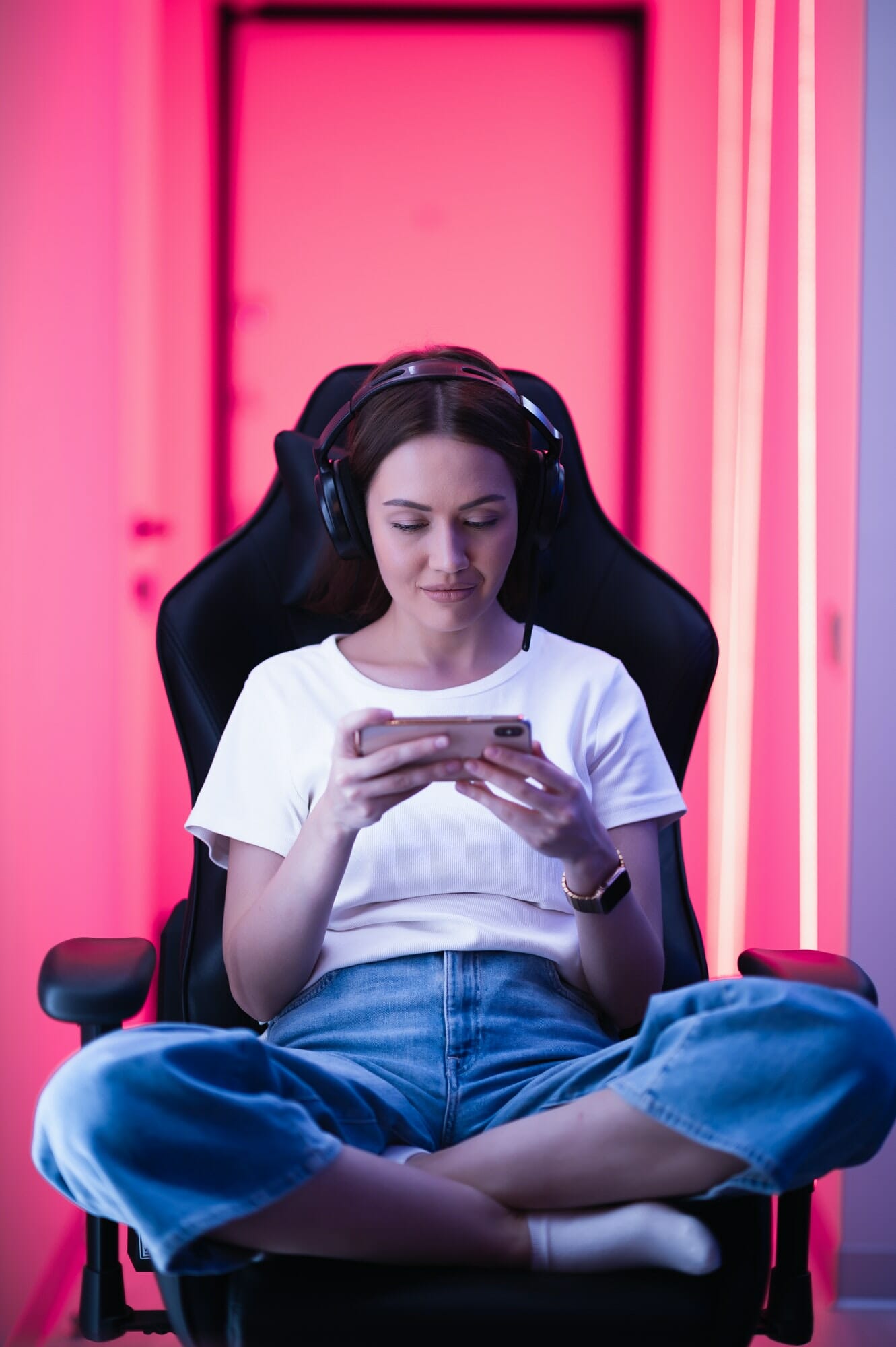 Cybersport gamer playing mobile game on the smart phone sitting on a gaming chair in neon color room, Game Development for Content Creators