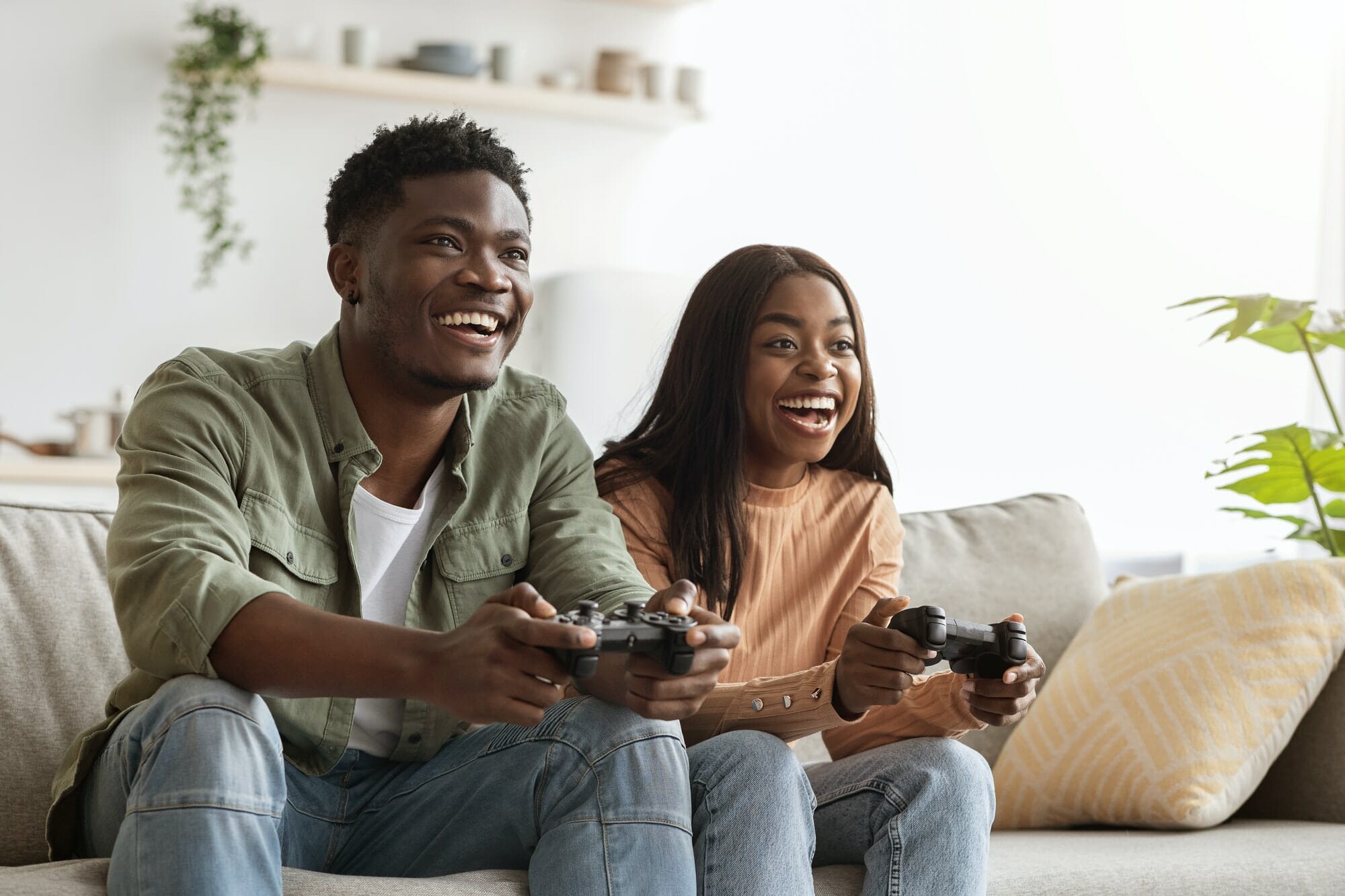 Joyful black couple playing video games at home
