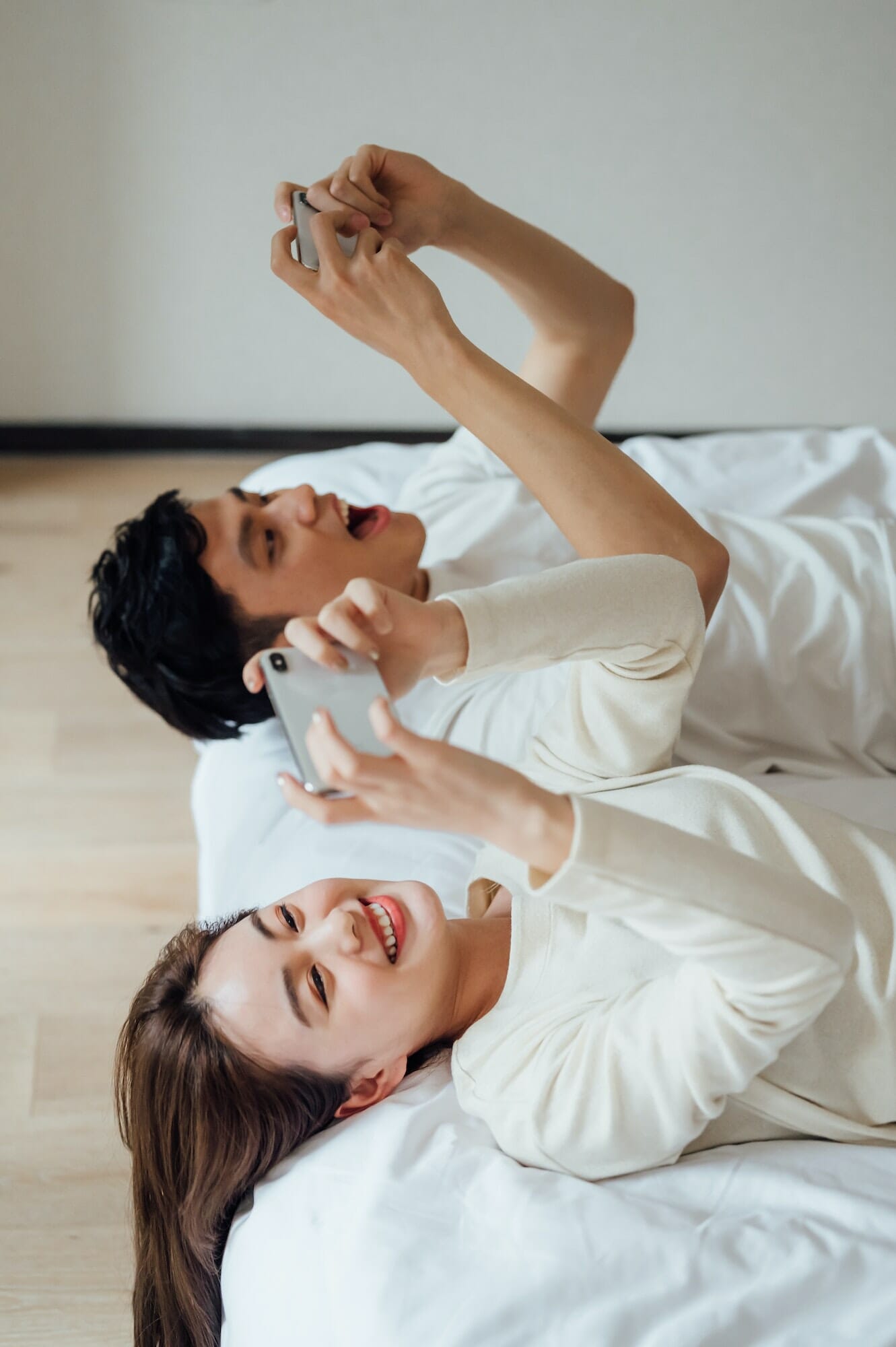 Young couple playing online games with smartphone in bedroom