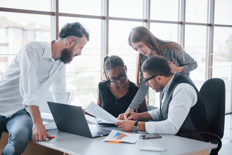 young-employees-sitting-office-table-using-laptop_146671-15632