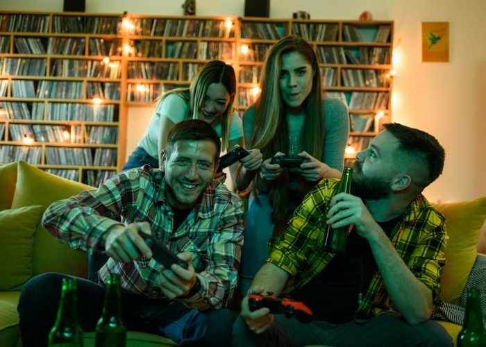 Friends gathered at home playing video games on a console.