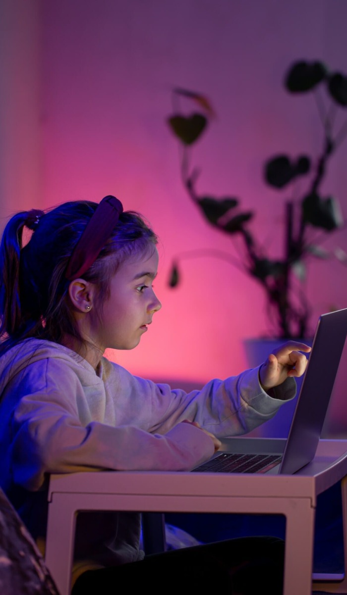 A little girl uses a laptop late at night.