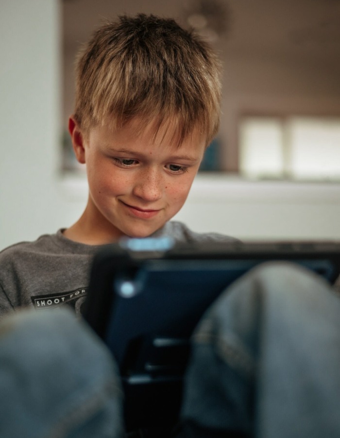 A smiling happy Caucasian boy is playing on iPad (electronic device), video games, using technology