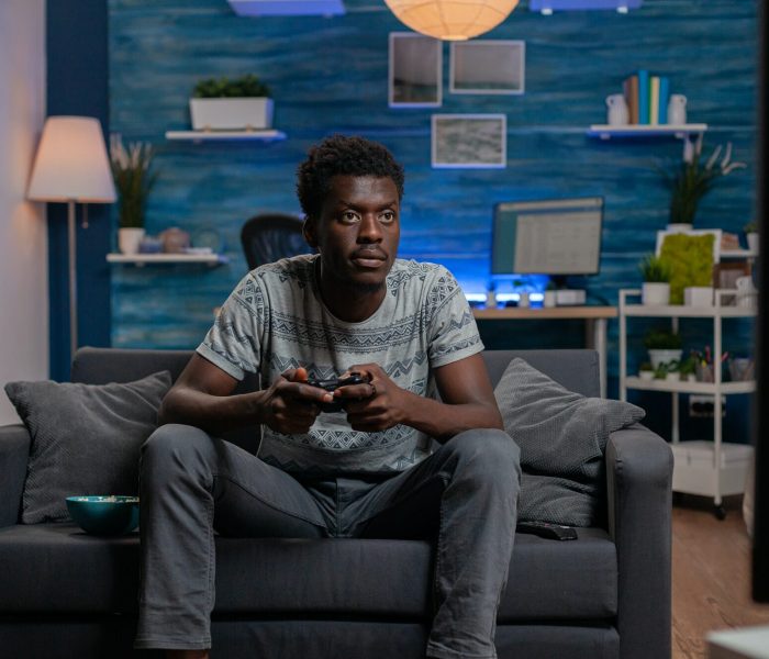 African american player young man holding gaming joystick playing online videogames