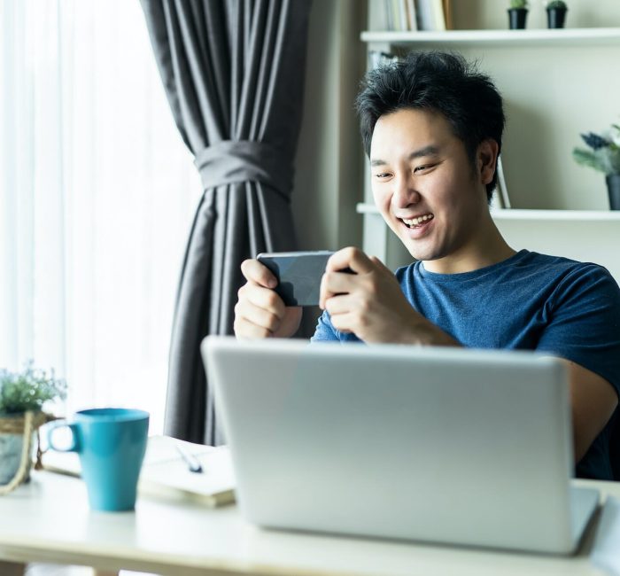 Mobile Game Development for iOS Devices Person playing a mobile game on their phone in a cozy home office setting.