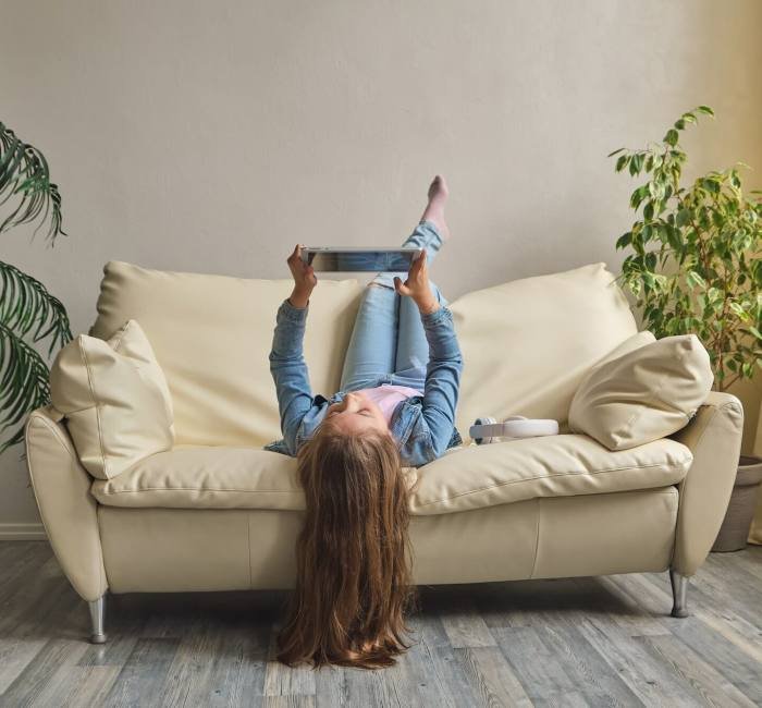 Child playing on ipad tablet pc on the sofa at home