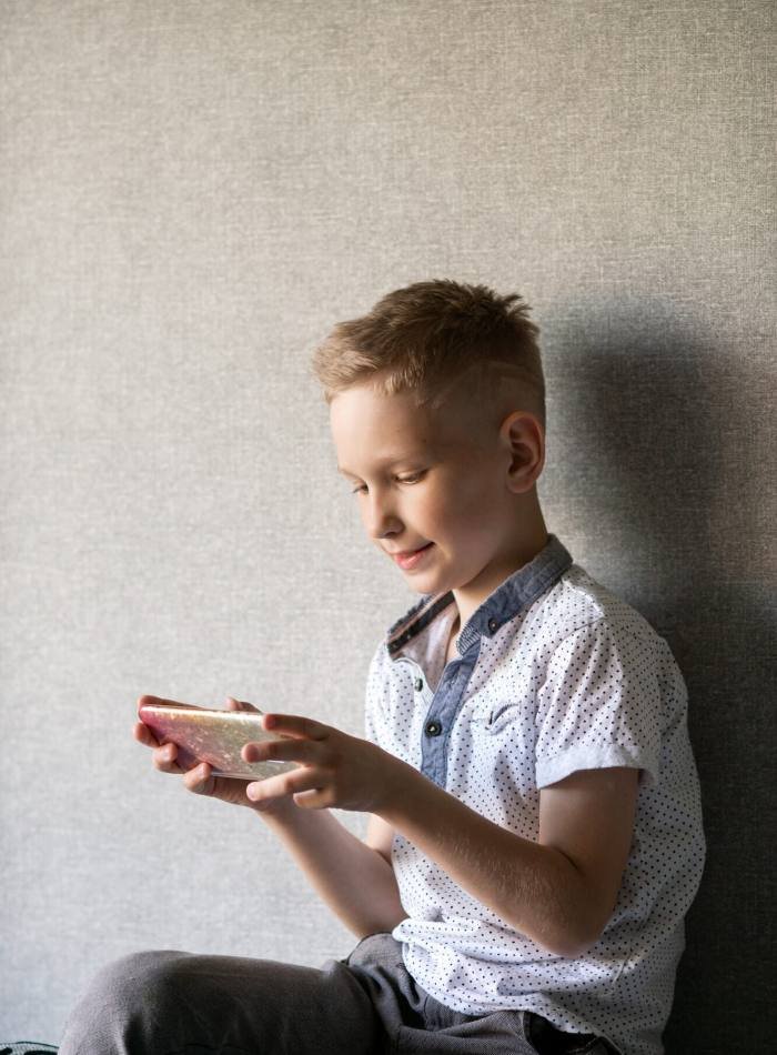 Cute boy looks at the phone and smiles