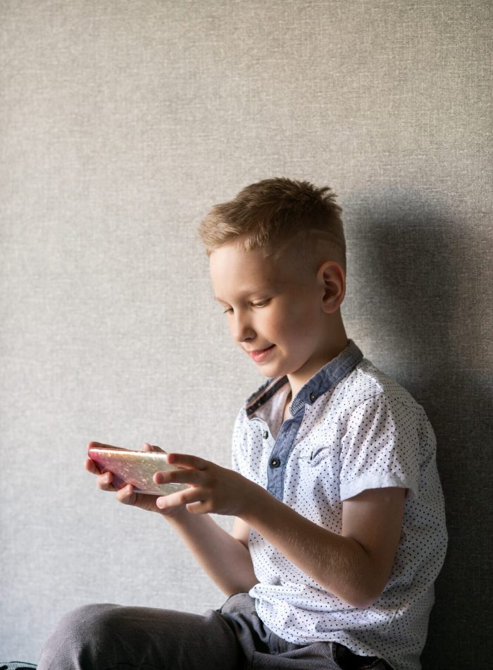 Boy Smiling While Engaged in a VR Game on His Phone