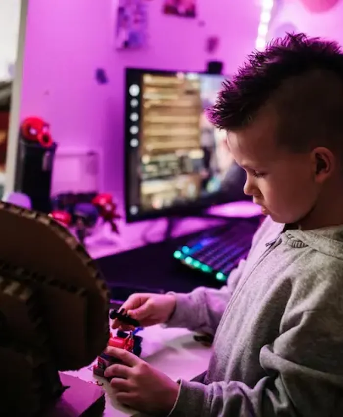 Child playing with toys while a computer screen displays a game