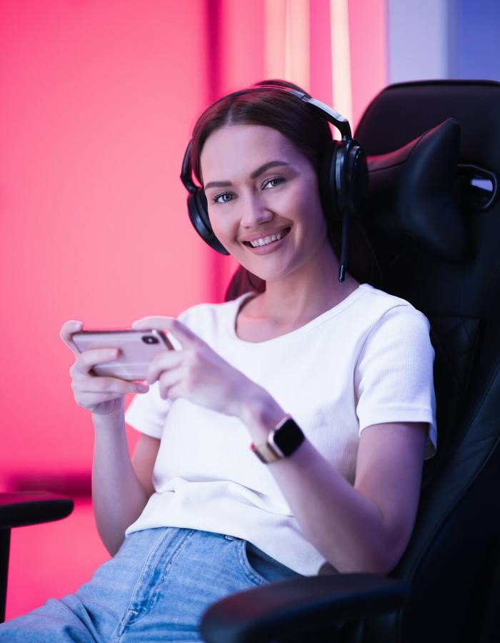 Cybersport gamer playing mobile game on the smart phone sitting on a gaming chair in neon color room