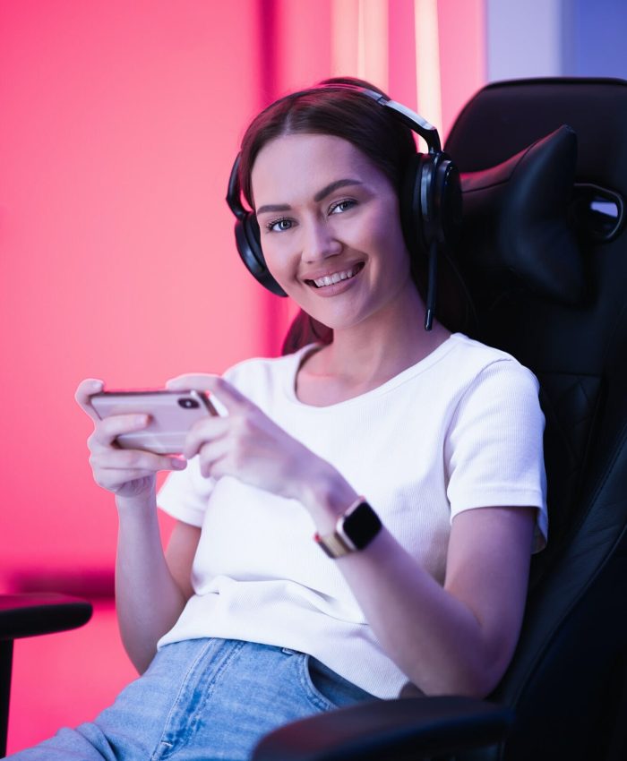 Gamer in neon-lit room playing mobile game, ideal for marketing mobile titles.