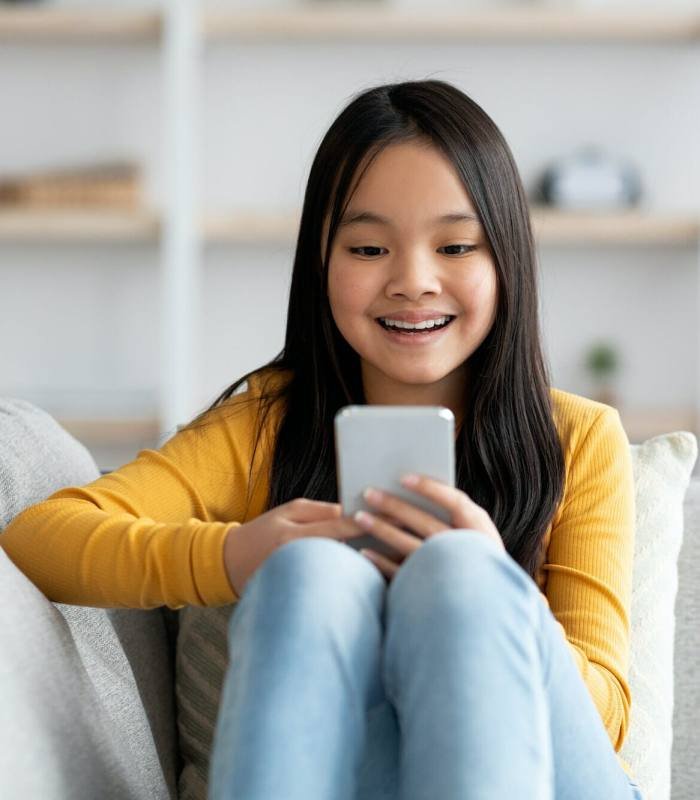 Happy asian girl schooler playing games on cellphone