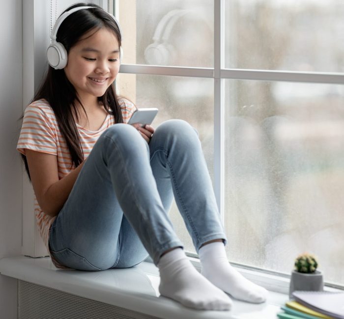 Smiling child with headset using smartphone, representing mobile game engagement for marketing campaigns.