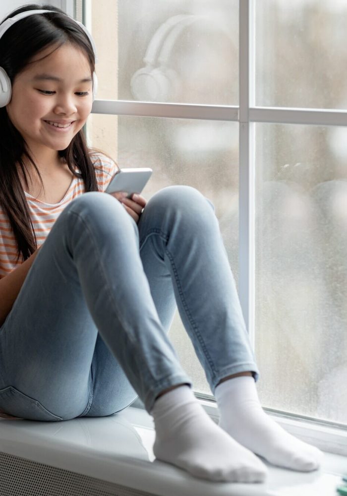 Video Game Marketing Agency for Family-Friendly Games Smiling child with headset using smartphone, representing mobile game engagement for marketing campaigns.