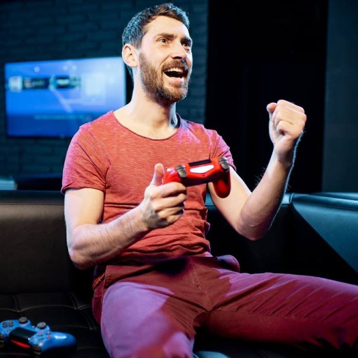 Happy man playing video games with gaming console in the club