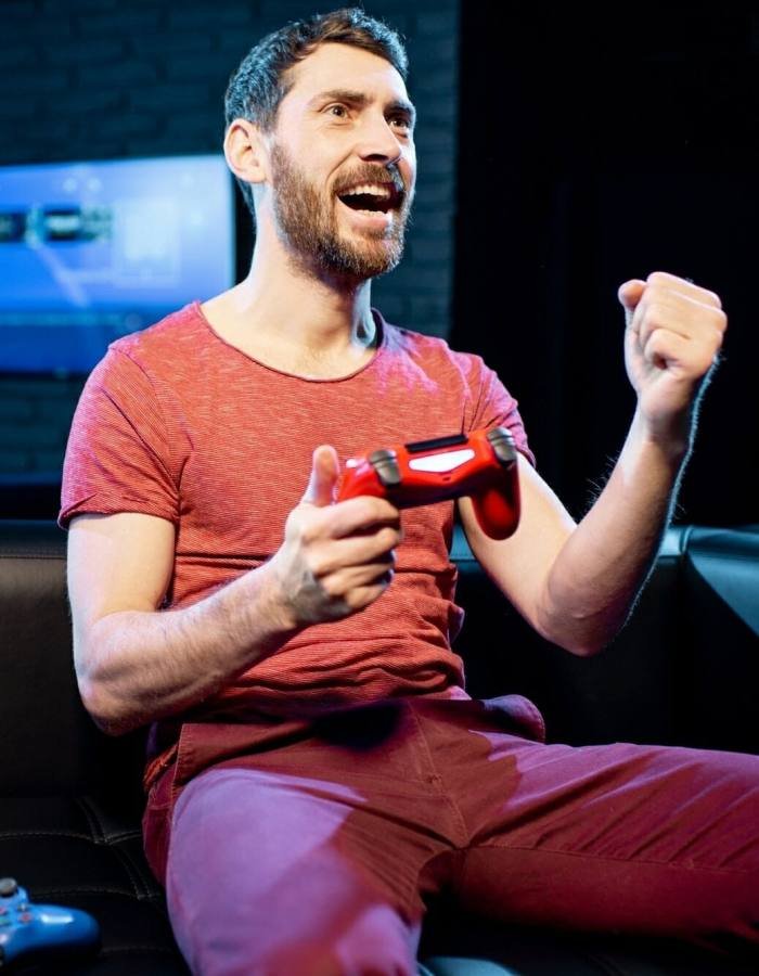 Happy man playing video games with gaming console in the club