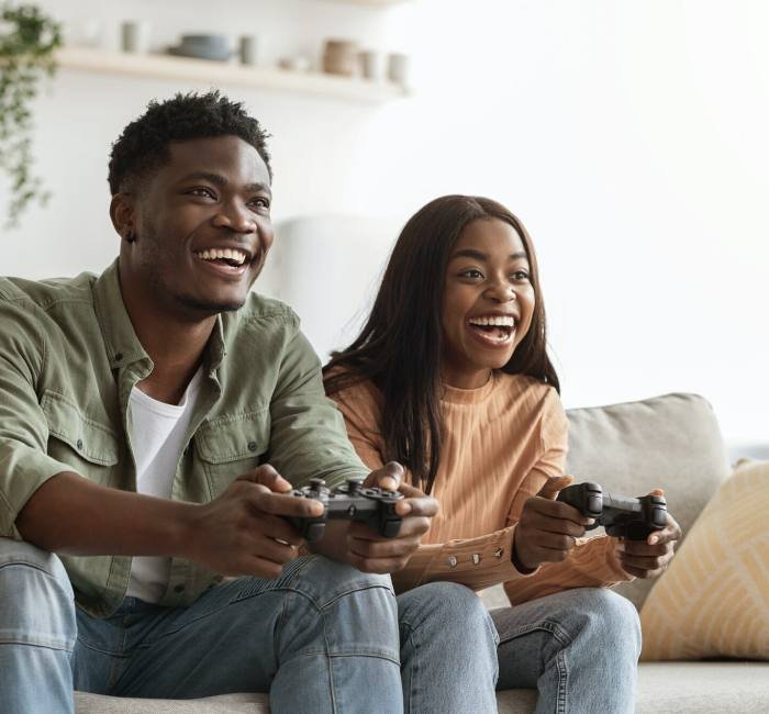 Joyful black couple playing video games at home