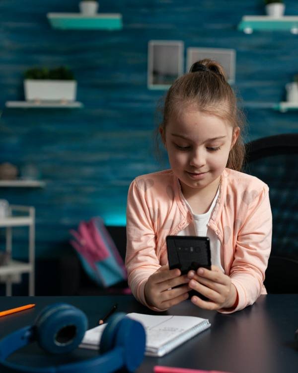 Little schoolchild holding modern smartphone