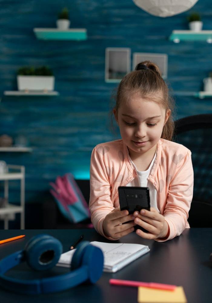 Little schoolchild holding modern smartphone