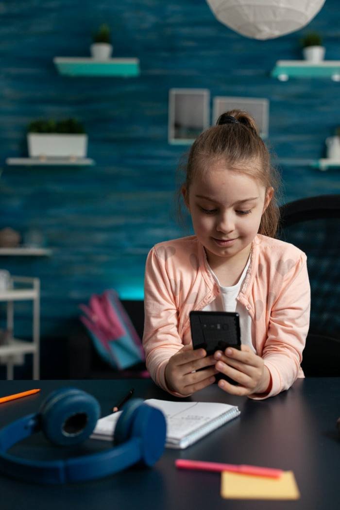 Little schoolchild holding modern smartphone