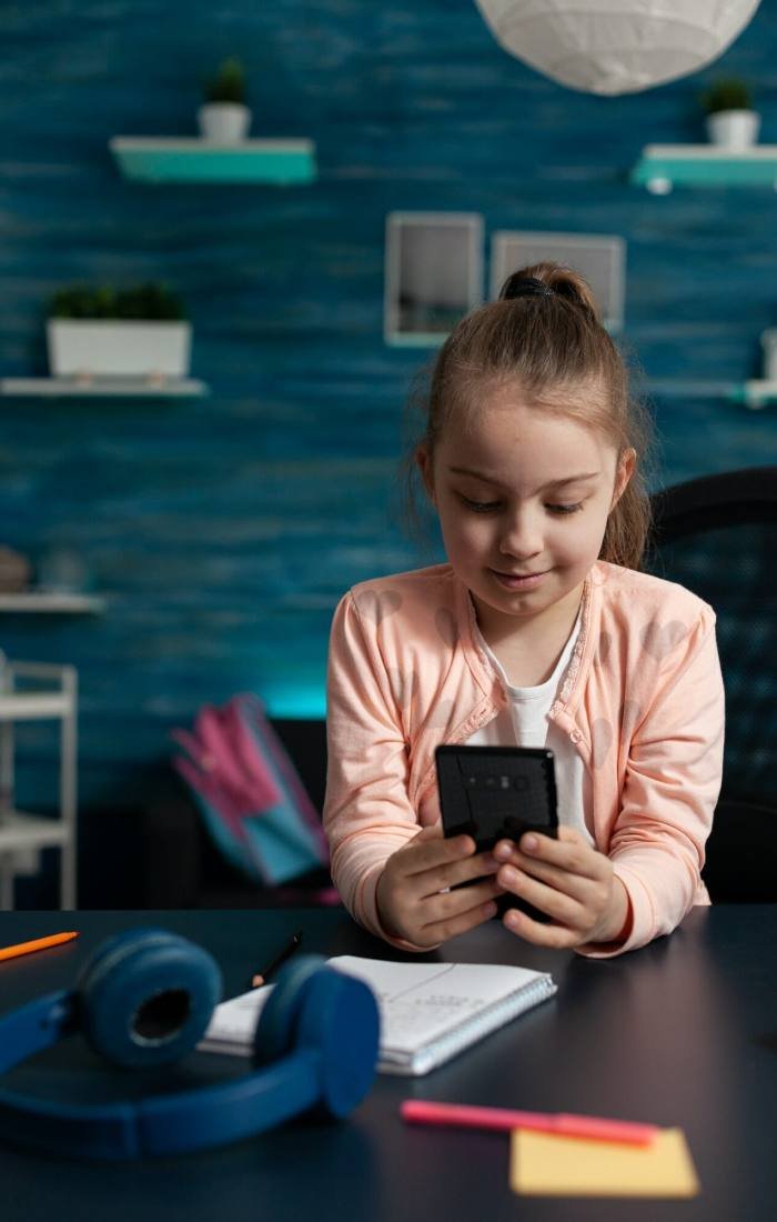 Little schoolchild holding modern smartphone