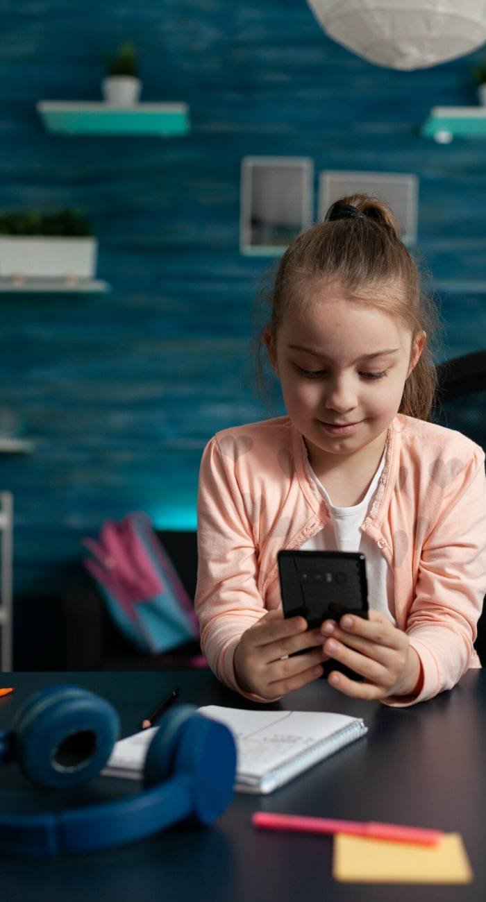 Little schoolchild holding modern smartphone