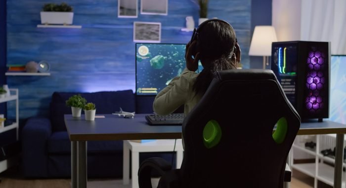 Gamer immersed in a shooter game with RGB lighting and high-end setup.
