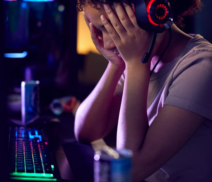 Stressed Teenage Girl Being Bullied Online Whilst Gaming At Home