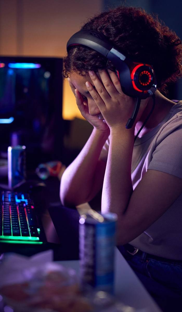 Stressed Teenage Girl Being Bullied Online Whilst Gaming At Home