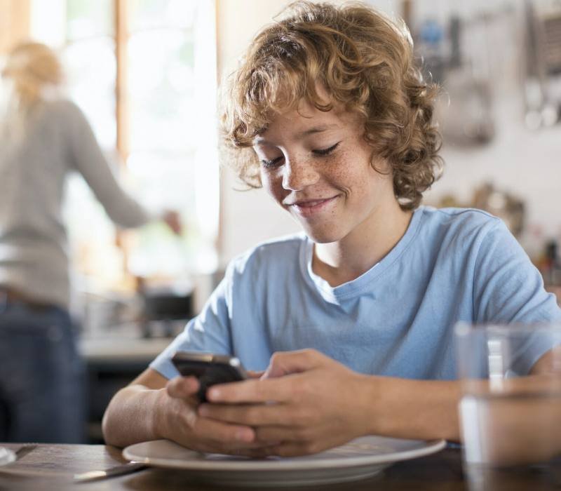 Teenage boy using smartphone at dining table