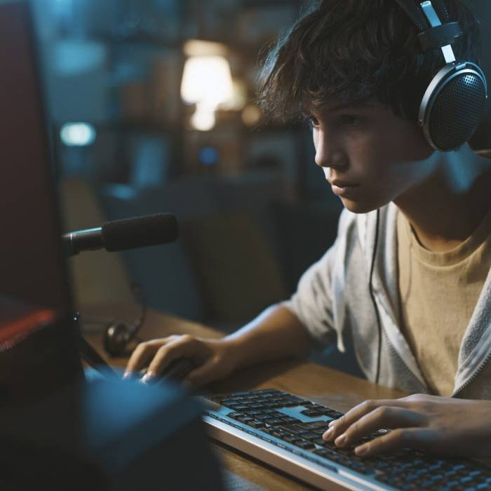 Teenager wearing headphones and playing online puzzle video games