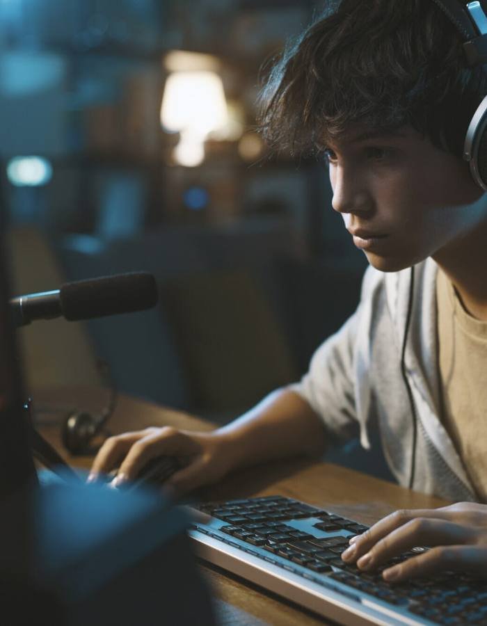 Teenager wearing headphones and playing online puzzle video games