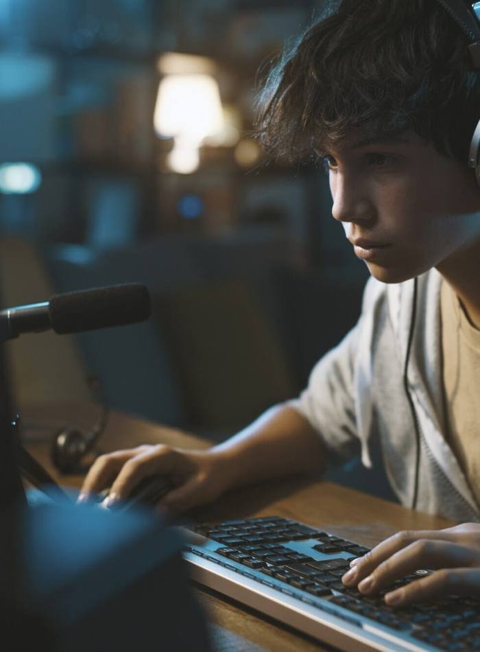 Teenager wearing headphones and playing online puzzle video games