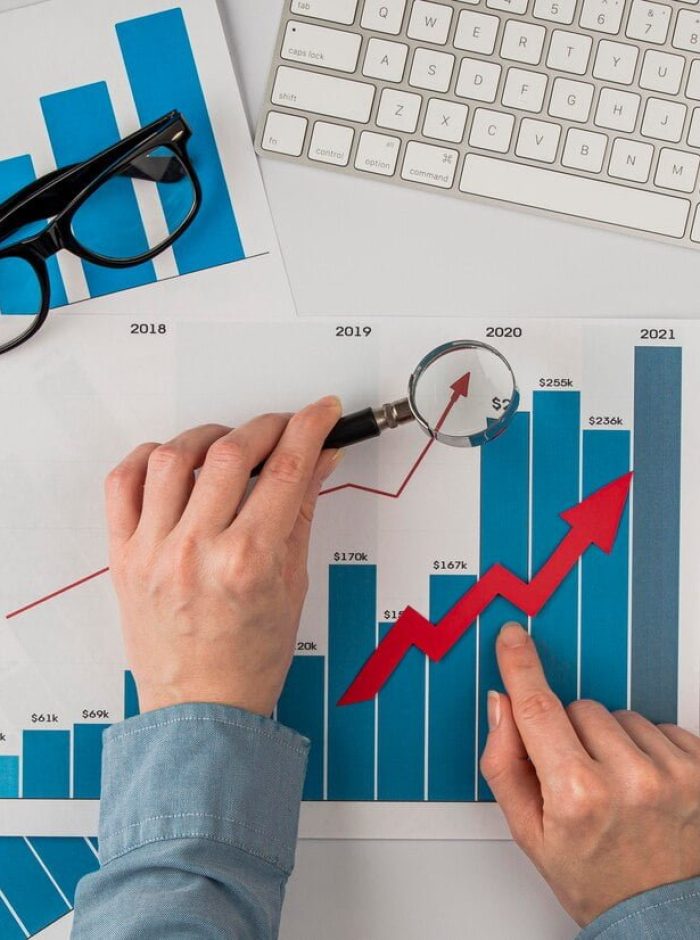 top-view-office-desk-with-growth-chart-hands-holding-magnifying-glass_23-2148780614