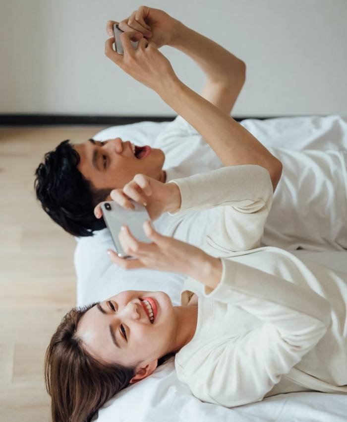 Young couple playing online games with smartphone in bedroom