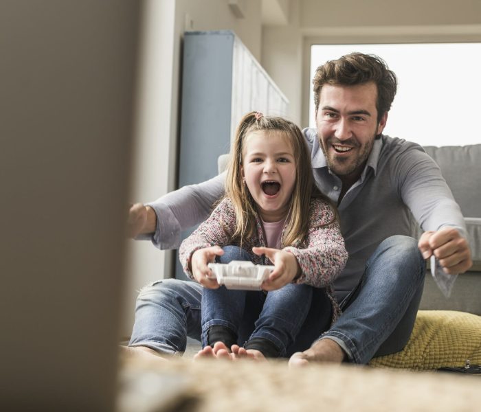 Young man and little girl playing computer game with gaming console